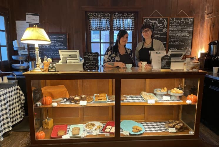 Two people standing behind a display case filled with cookies and pastries