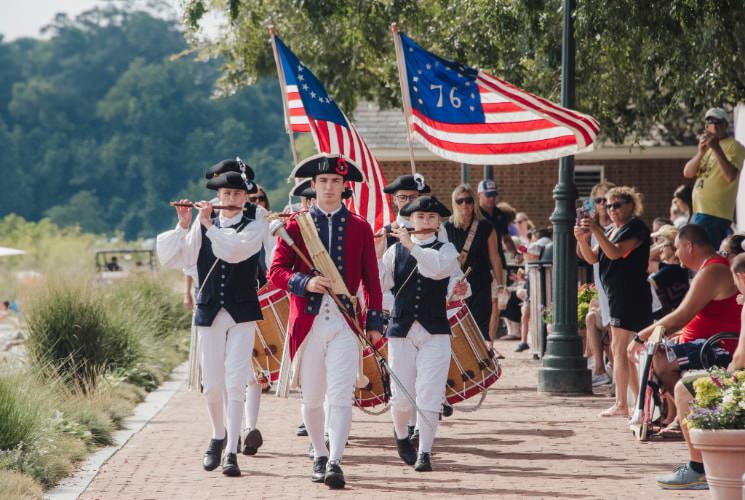 Marching band dressed in American Colonial uniforms performing for people