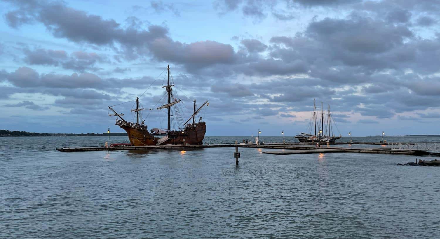 Old sailing ship tied to a dock with cloudy skies in the background