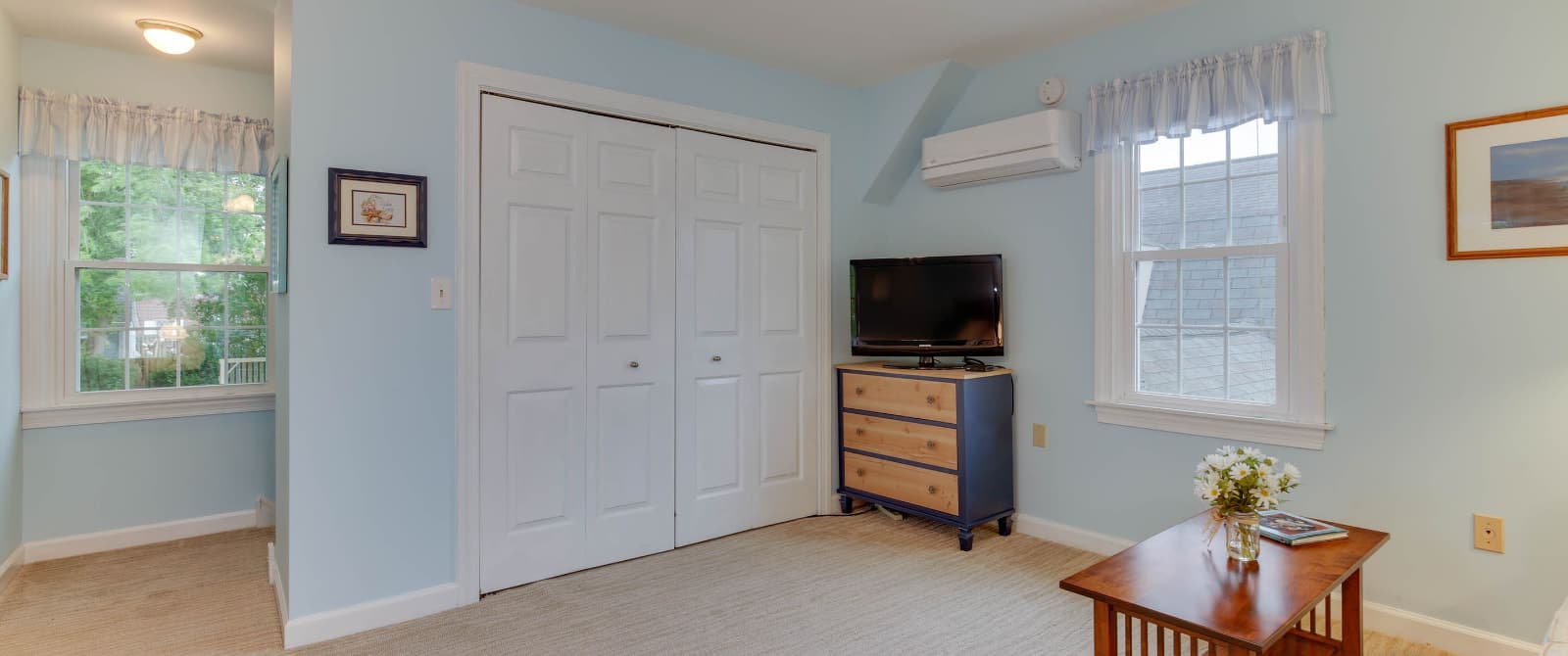 Suite with light blue walls, carpeting, wood coffee table, flatscreen TV, and white closet doors