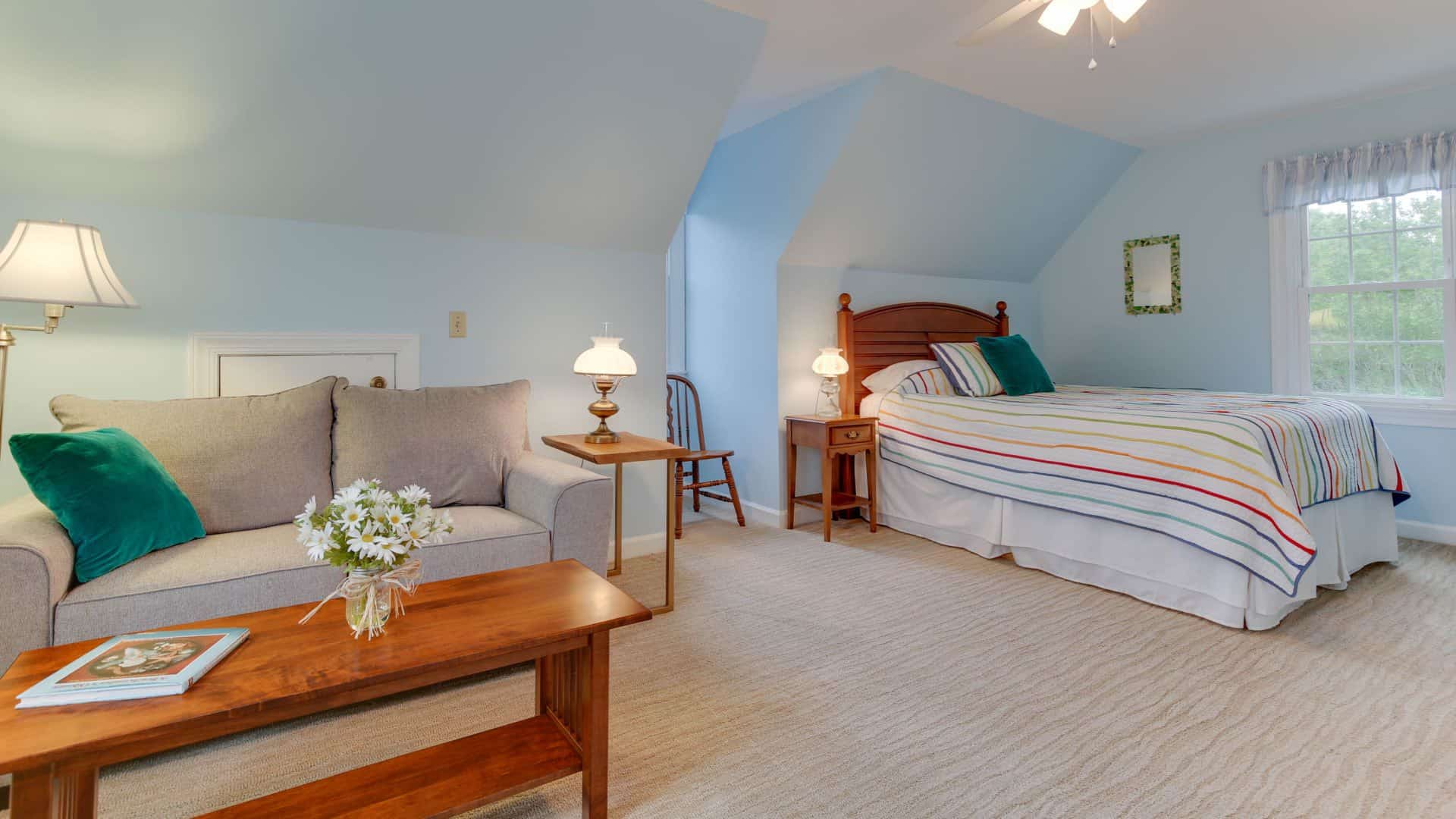 Bedroom with light blue walls, carpeting, light gray upholstered sofa, and wood coffee table