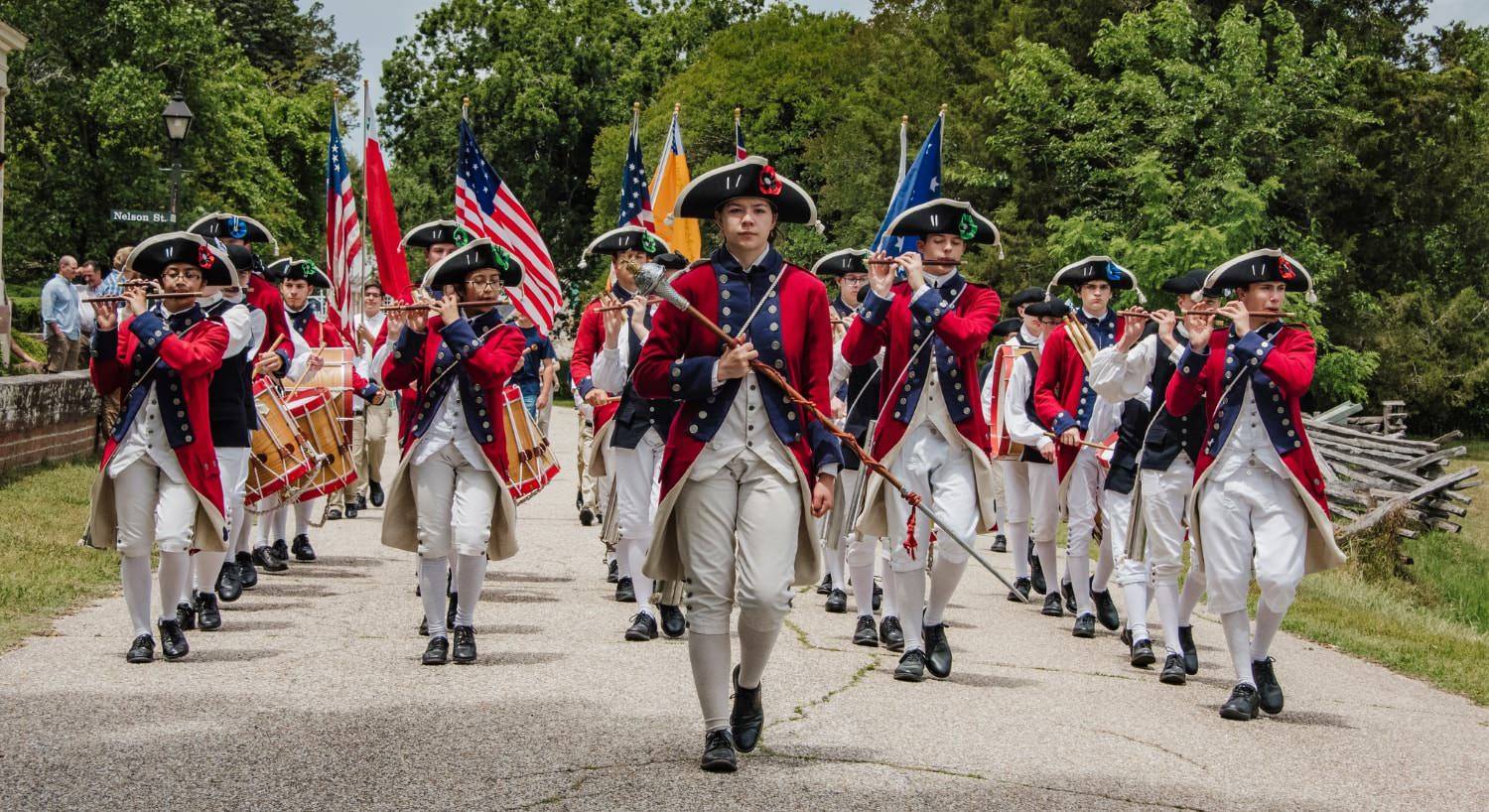 Marching band dressed in American Colonial uniforms performing for people